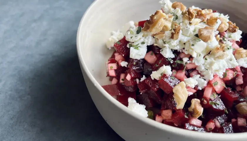 Schüssel mit roter Bete, Feta und Walnüssen. Ein köstlicher roter Bete Feta Salat, garniert mit Kräutern.
