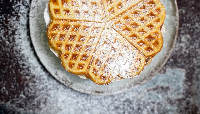 Herzförmige Waffeln, bestäubt mit Puderzucker, ein köstliches Rezept für süße Momente.