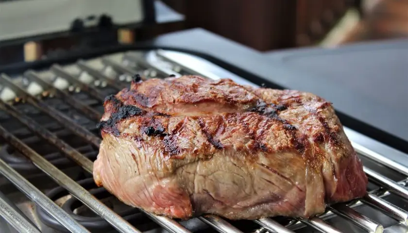 Ein saftiges Steak brutzelt auf einem Elektrogrill. Die Grillstreifen sind deutlich sichtbar, und das Fleisch ist perfekt gebräunt.