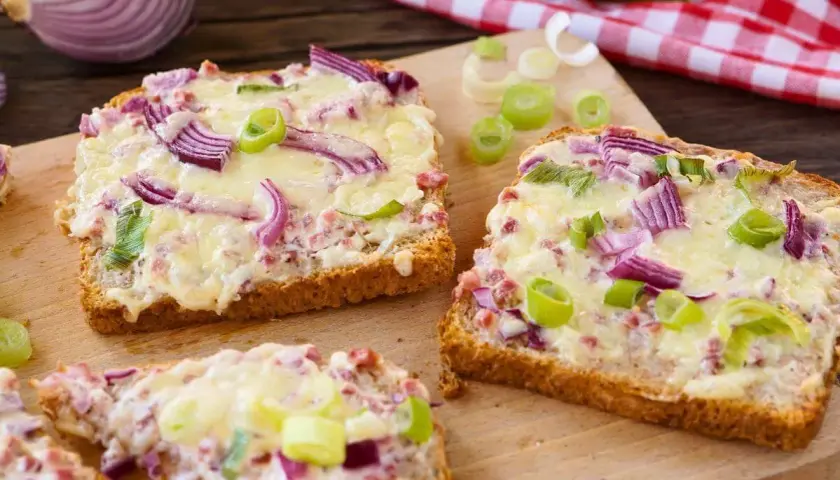 Drei Scheiben Brot mit geschmolzenem Käse, roten Zwiebeln und Frühlingszwiebeln. Ein schnelles Abendessen, warm und lecker.