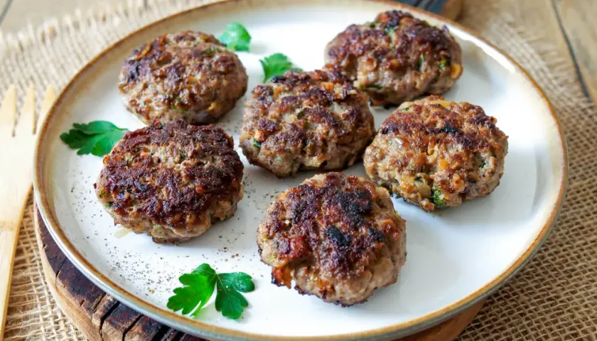 Sechs goldbraune Buletten, frisch gebraten, liegen auf einem Teller. Ein einfaches, aber köstliches Buletten Rezept.