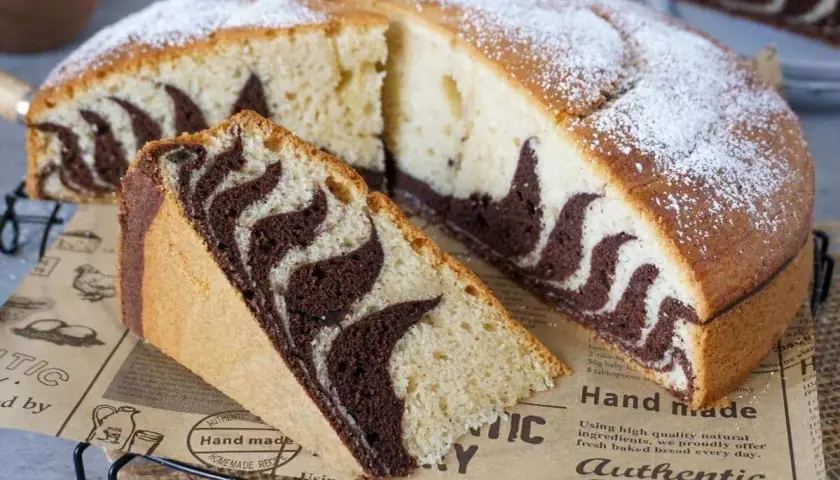 Ein saftiger Zebrakuchen, perfekt für das Zebrakuchen Rezept. Mit Puderzucker bestäubt und einem Stück zum Probieren.