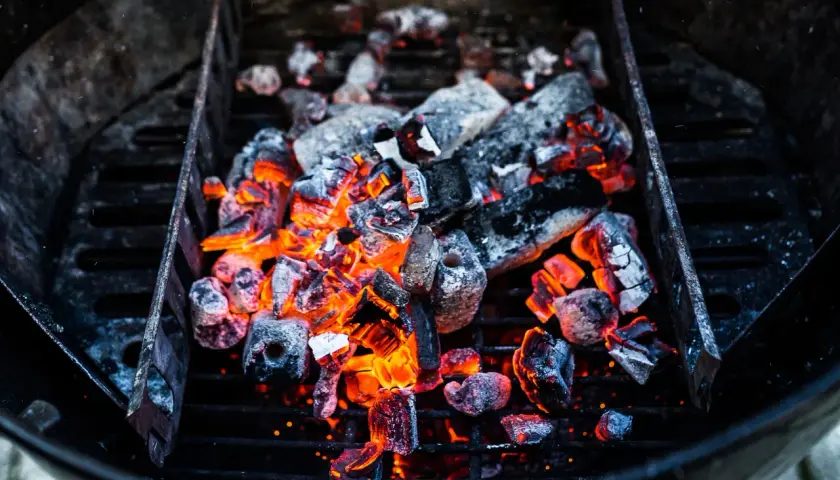 Glühende Kohlen im Grill, bereit für das perfekte Barbecue. Die Frage "wie viel Kohle zum Grillen" stellt sich hier nicht, denn diese Menge verspricht Hitze und Genuss.