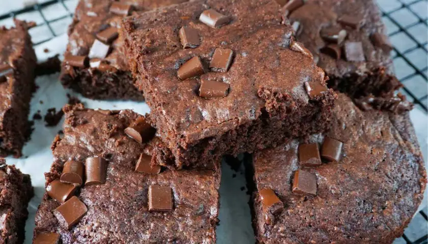Saftige Zucchini Brownies mit Schokostückchen, auf einem Gitterrost arrangiert.