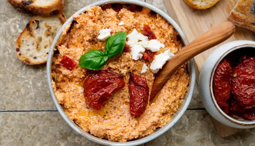 Cremiger Feta-Dip mit getrockneten Tomaten, Basilikum und Brot.
