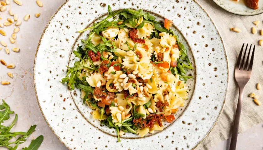 Mediterraner Salat mit Farfalle, getrockneten Tomaten, Rucola und Pinienkernen. Ein leichter Genuss!