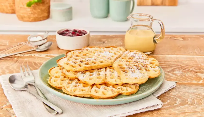 Leckere Waffeln ohne Ei, bestäubt mit Puderzucker, serviert mit Marmelade und Vanillesauce. Ein Genuss für jeden Tag!