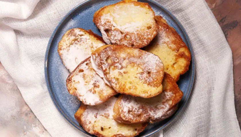 Ein Teller mit goldbraunem French Toast, bestäubt mit Puderzucker. Ein süßer Genuss für jeden Morgen.
