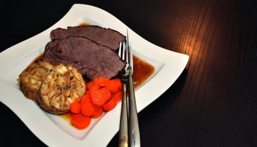 Saftiger Rinderbraten im Dutch Oven, serviert mit Klößen und Karotten. Ein Klassiker, der auf der Zunge zergeht.