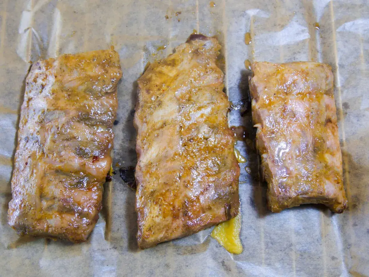 Drei saftige spareribs sous vide, mariniert und auf Backpapier liegend, bereit zum Genuss.
