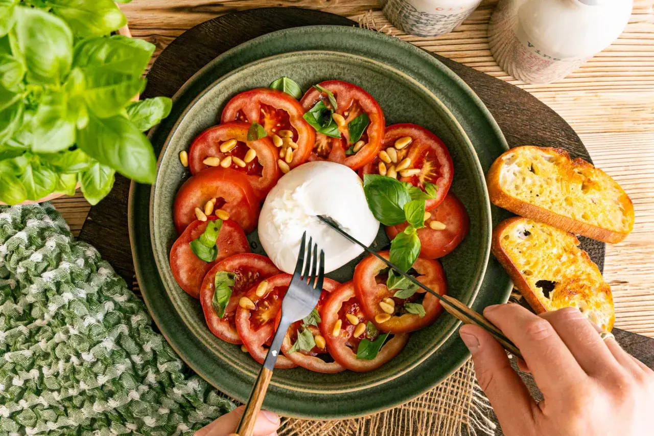 Frischer Burrata mit Tomaten, Pinienkernen und Basilikum, perfekt für leichte Burrata Rezepte. Dazu geröstetes Brot.