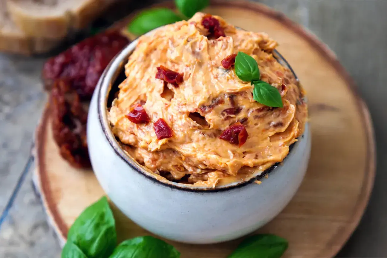 Cremige Tomatenbutter, garniert mit Basilikum und getrockneten Tomatenstücken. Ein köstliches Rezept für Tomatenbutter, perfekt zum Dippen oder Bestreichen.