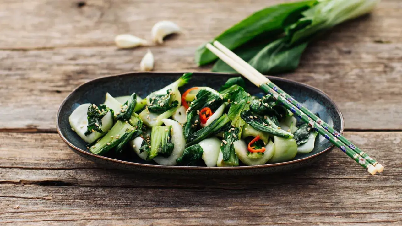 Ein Teller mit gebratenem Pak Choi, bestreut mit Sesam und Chili. Perfekt für einfache Pak Choi Rezepte.