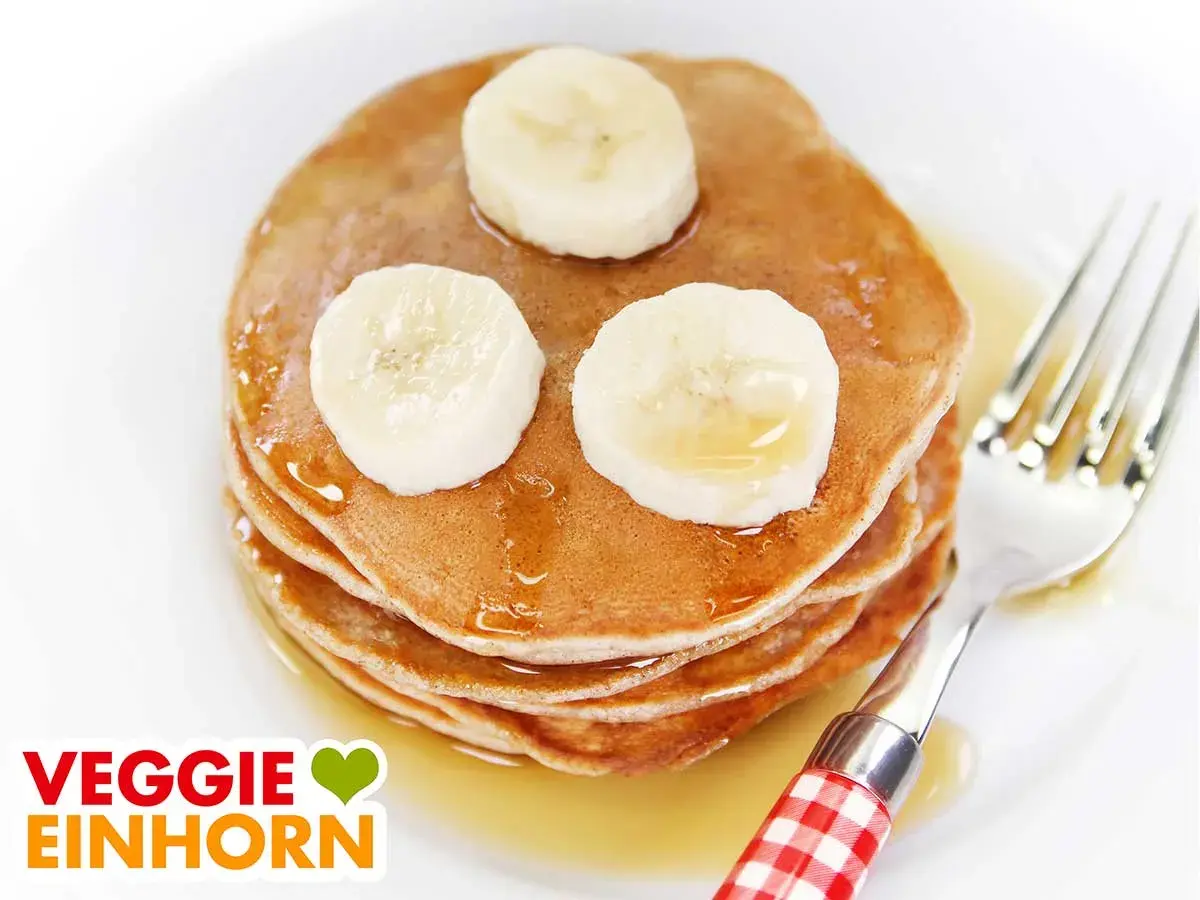 Leckere, fluffige bananen pancakes ohne ei, garniert mit Bananenscheiben und Sirup. Ein Genuss für jeden Morgen!