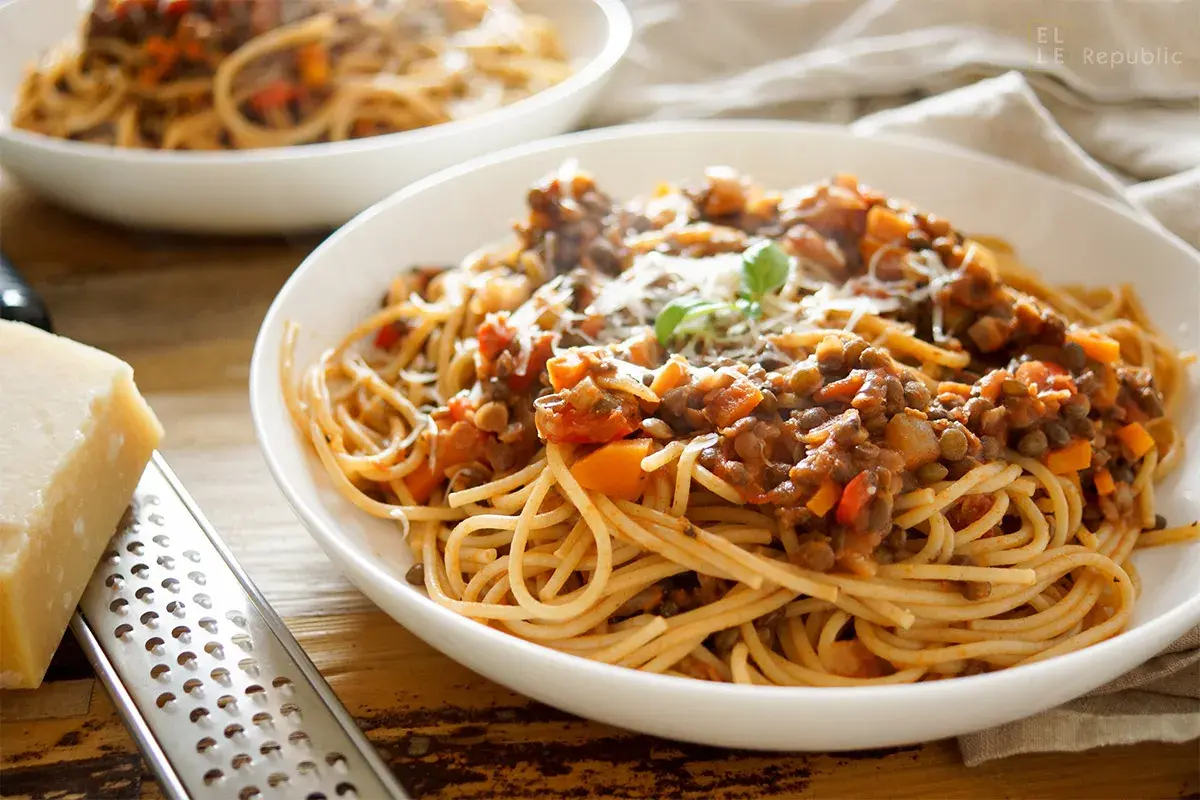 Herzhafte vegetarische Bolognese mit Linsen und Spaghetti, garniert mit Parmesan und Basilikum.