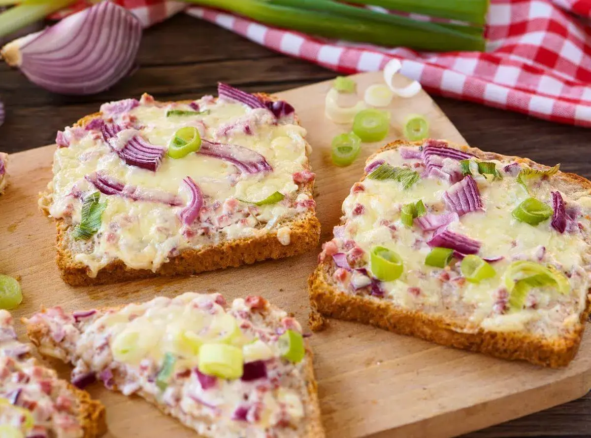Drei Scheiben Brot mit geschmolzenem Käse, roten Zwiebeln und Frühlingszwiebeln. Ein schnelles Abendessen, warm und lecker.