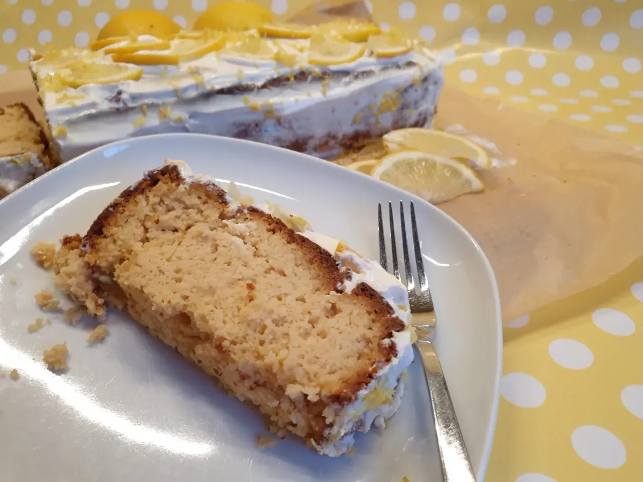 Ein Stück saftiger low carb Kuchen mit Zitronencreme und frischen Zitronenscheiben. Perfekt für Genießer!