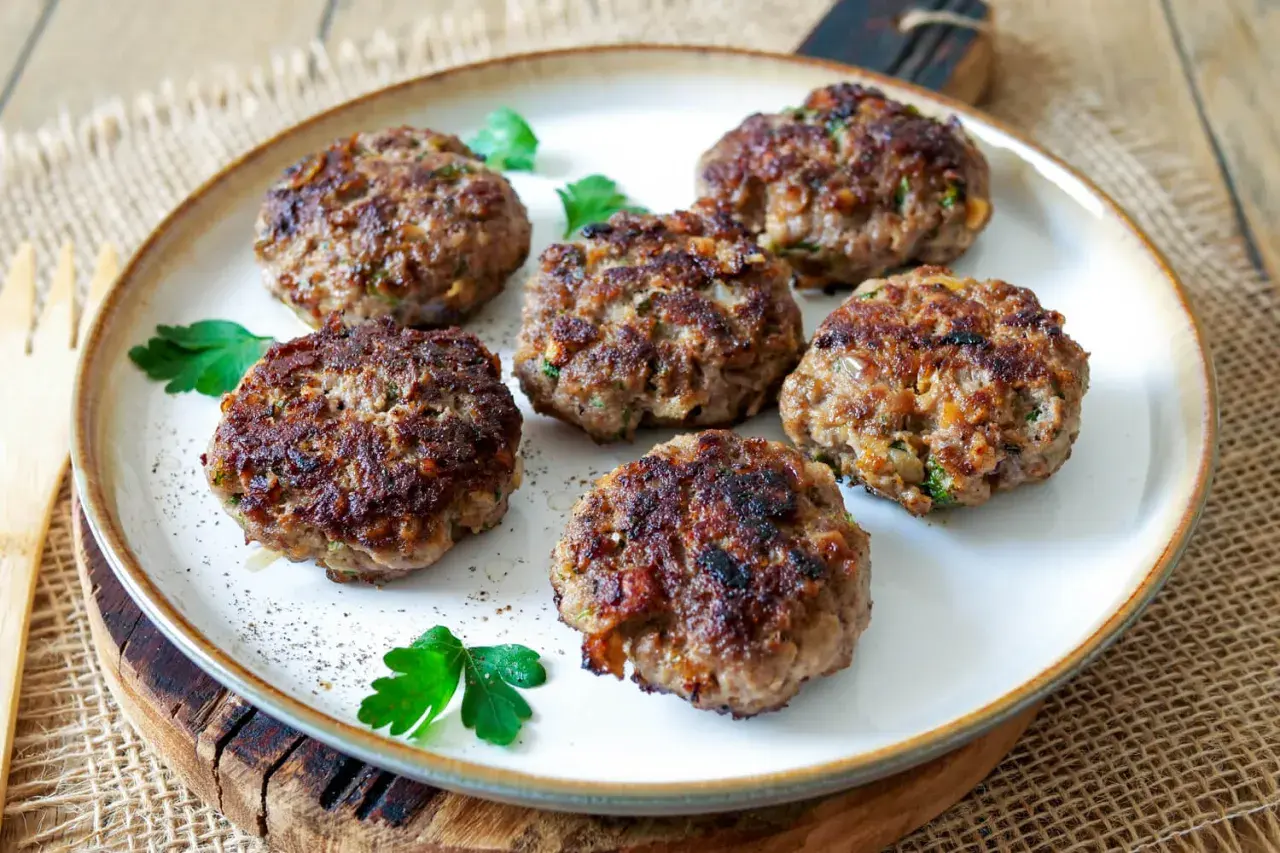 Sechs goldbraune Buletten, frisch gebraten, liegen auf einem Teller. Ein einfaches, aber köstliches Buletten Rezept.