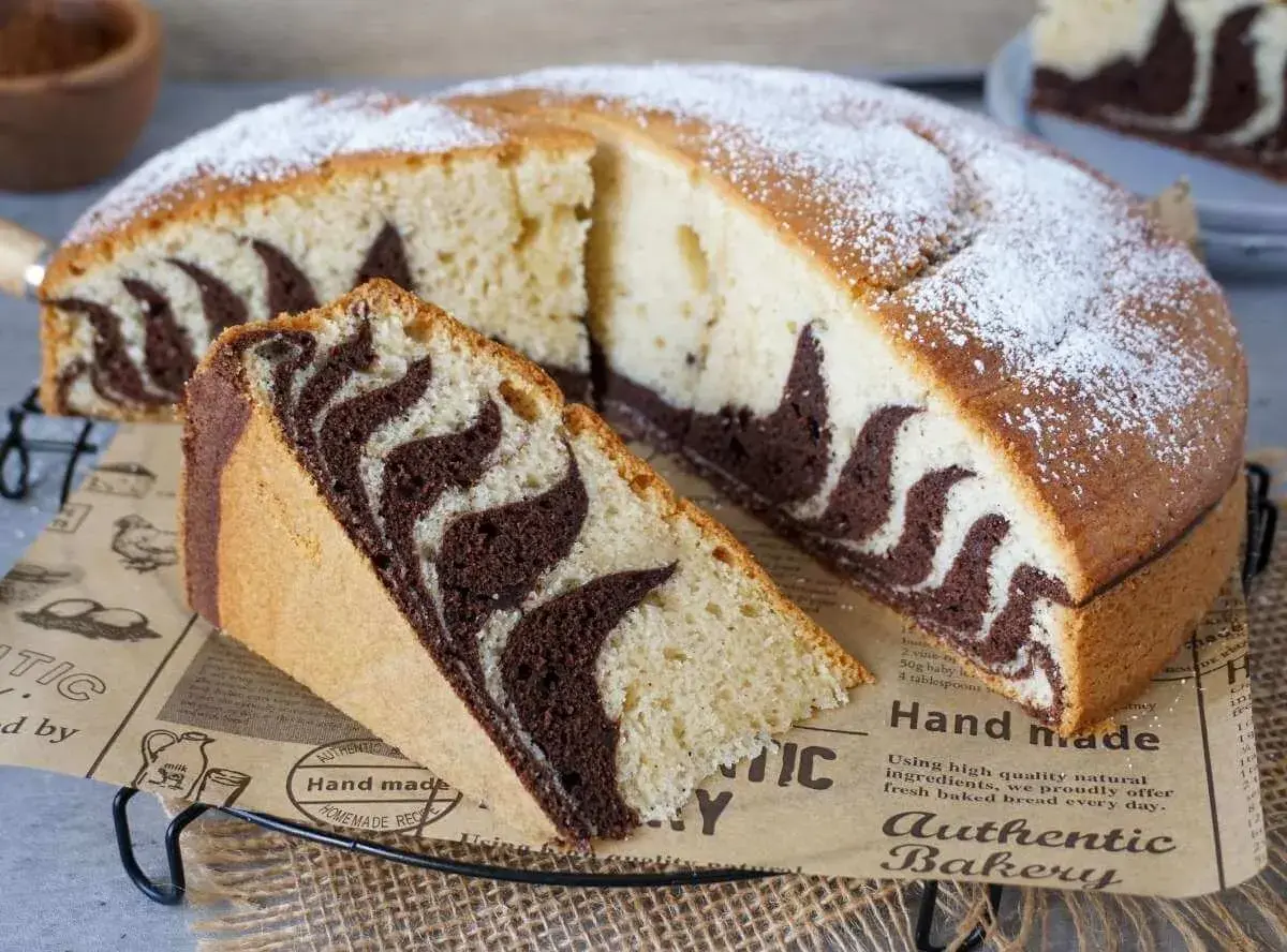 Ein saftiger Zebrakuchen, perfekt für das Zebrakuchen Rezept. Mit Puderzucker bestäubt und einem Stück zum Probieren.