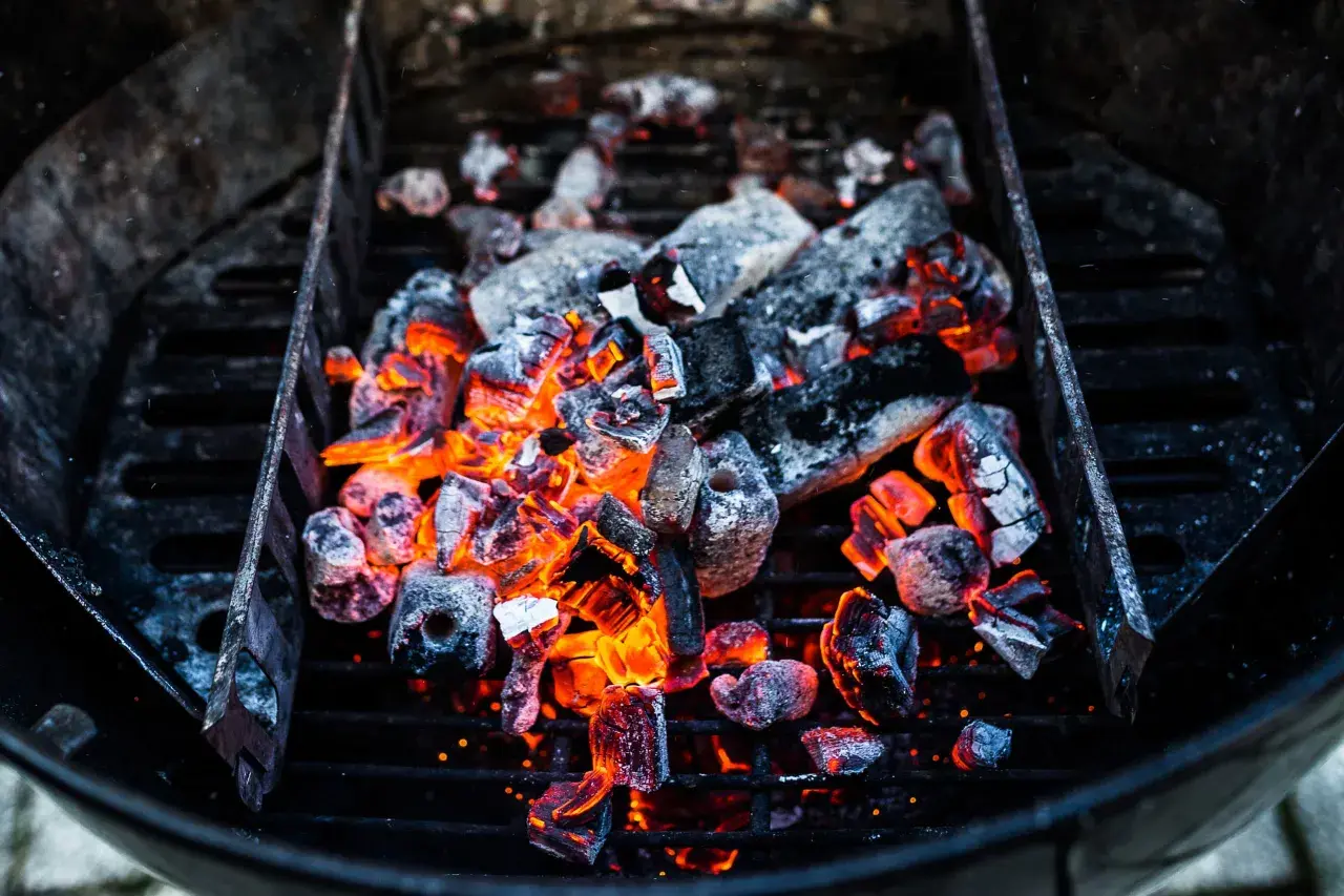 Glühende Kohlen im Grill, bereit für das perfekte Barbecue. Die Frage "wie viel Kohle zum Grillen" stellt sich hier nicht, denn diese Menge verspricht Hitze und Genuss.