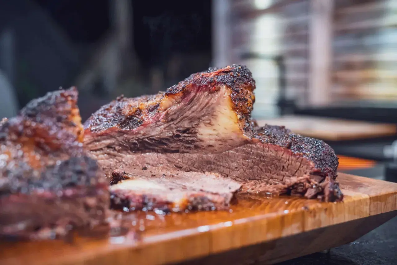 Saftiges Beef Brisket, welches Fleisch für BBQ-Liebhaber. Rauchig, zart und perfekt geschnitten auf einem Holzbrett.