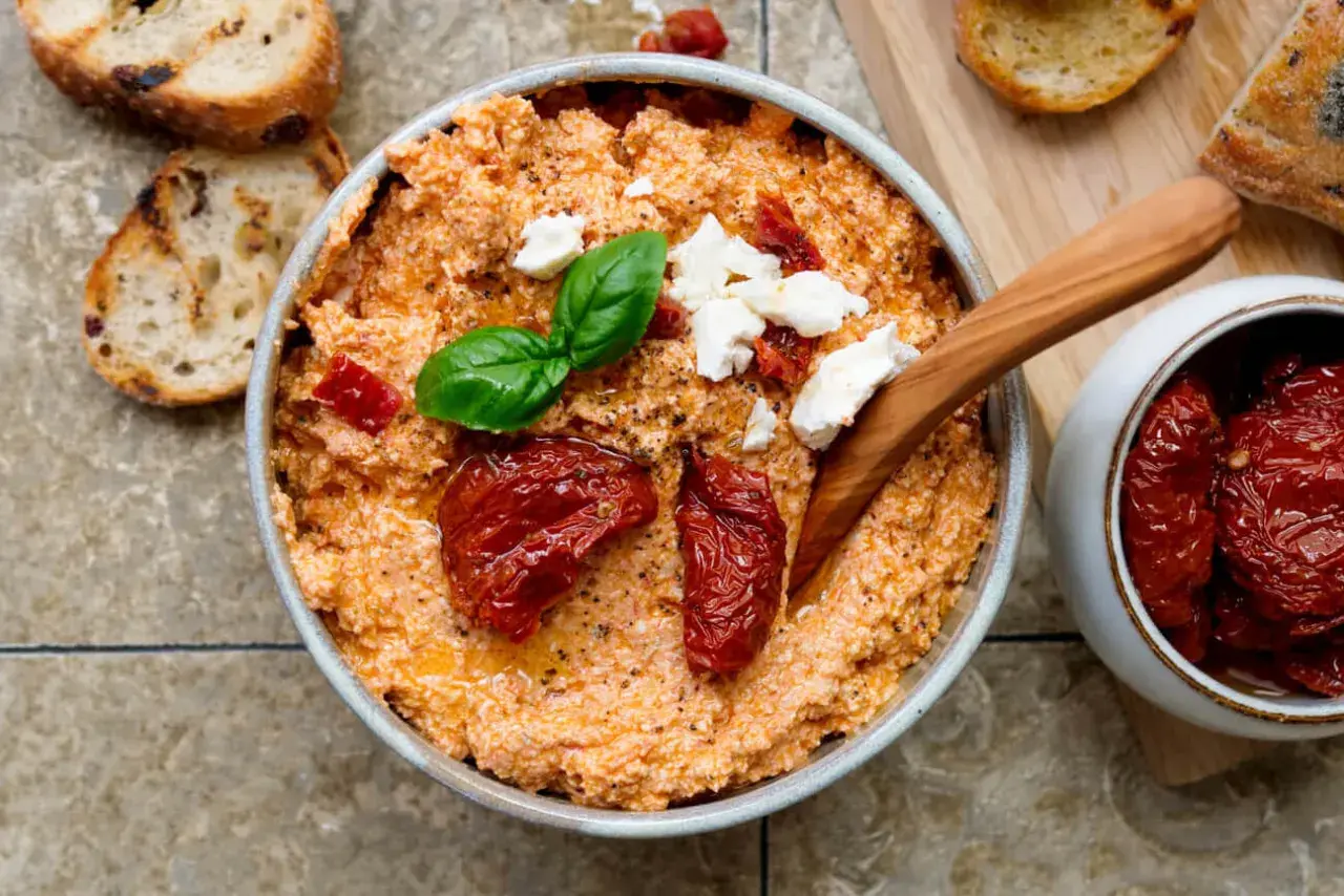 Cremiger Feta-Dip mit getrockneten Tomaten, Basilikum und Brot.
