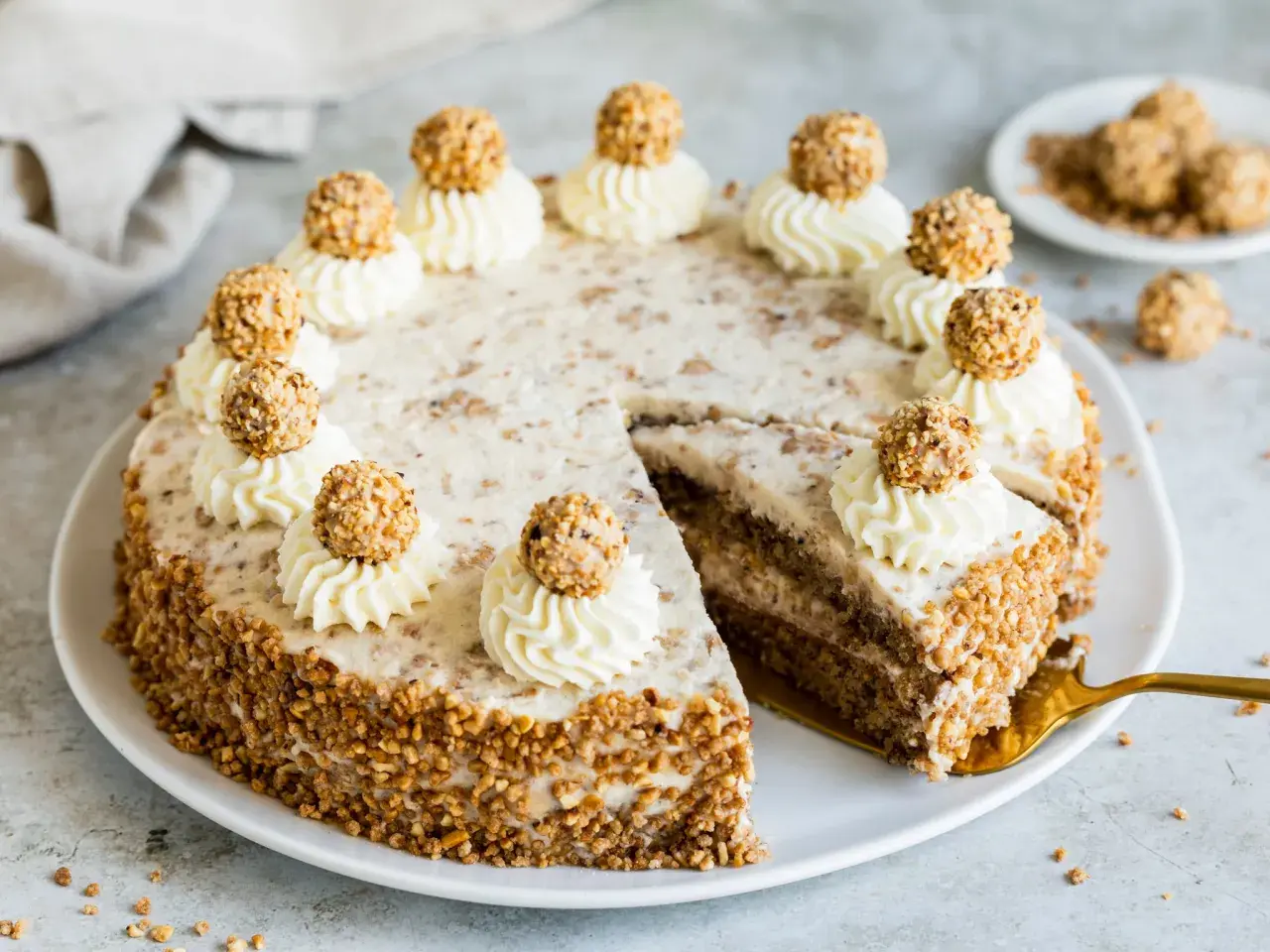 Eine köstliche Giotto Torte, verziert mit Sahnetuffs und Haselnusskugeln, umgeben von gehackten Nüssen.