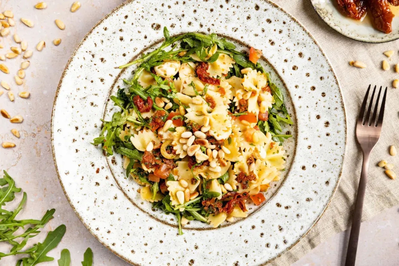 Mediterraner Salat mit Farfalle, getrockneten Tomaten, Rucola und Pinienkernen. Ein leichter Genuss!