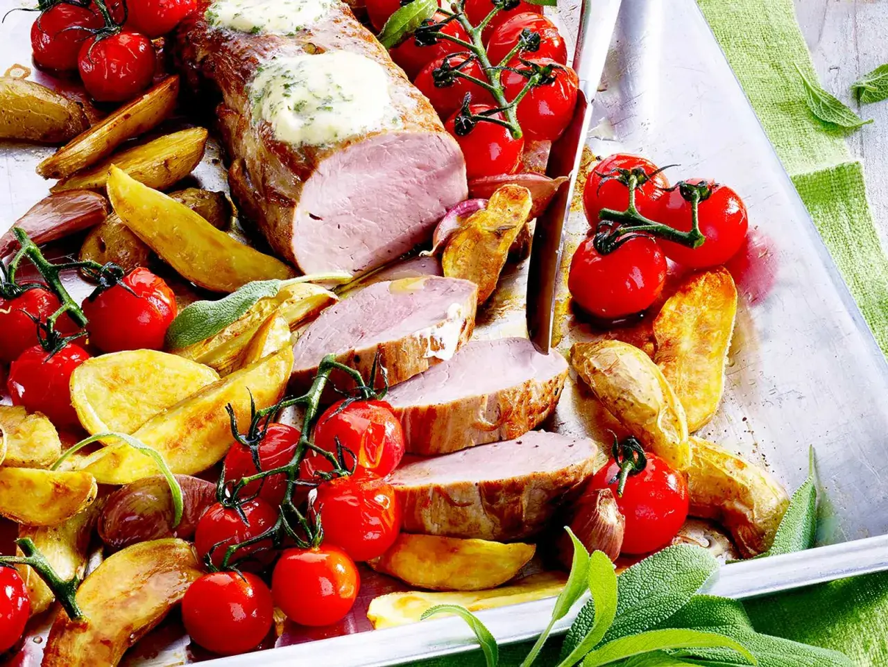 Saftiges Schweinefilet mit Kräuterbutter, dazu Rosmarinkartoffeln und Kirschtomaten. Ein köstliches Schweinefilet Rezept für Genießer.