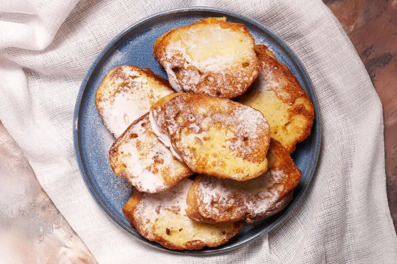 Ein Teller mit goldbraunem French Toast, bestäubt mit Puderzucker. Ein süßer Genuss für jeden Morgen.