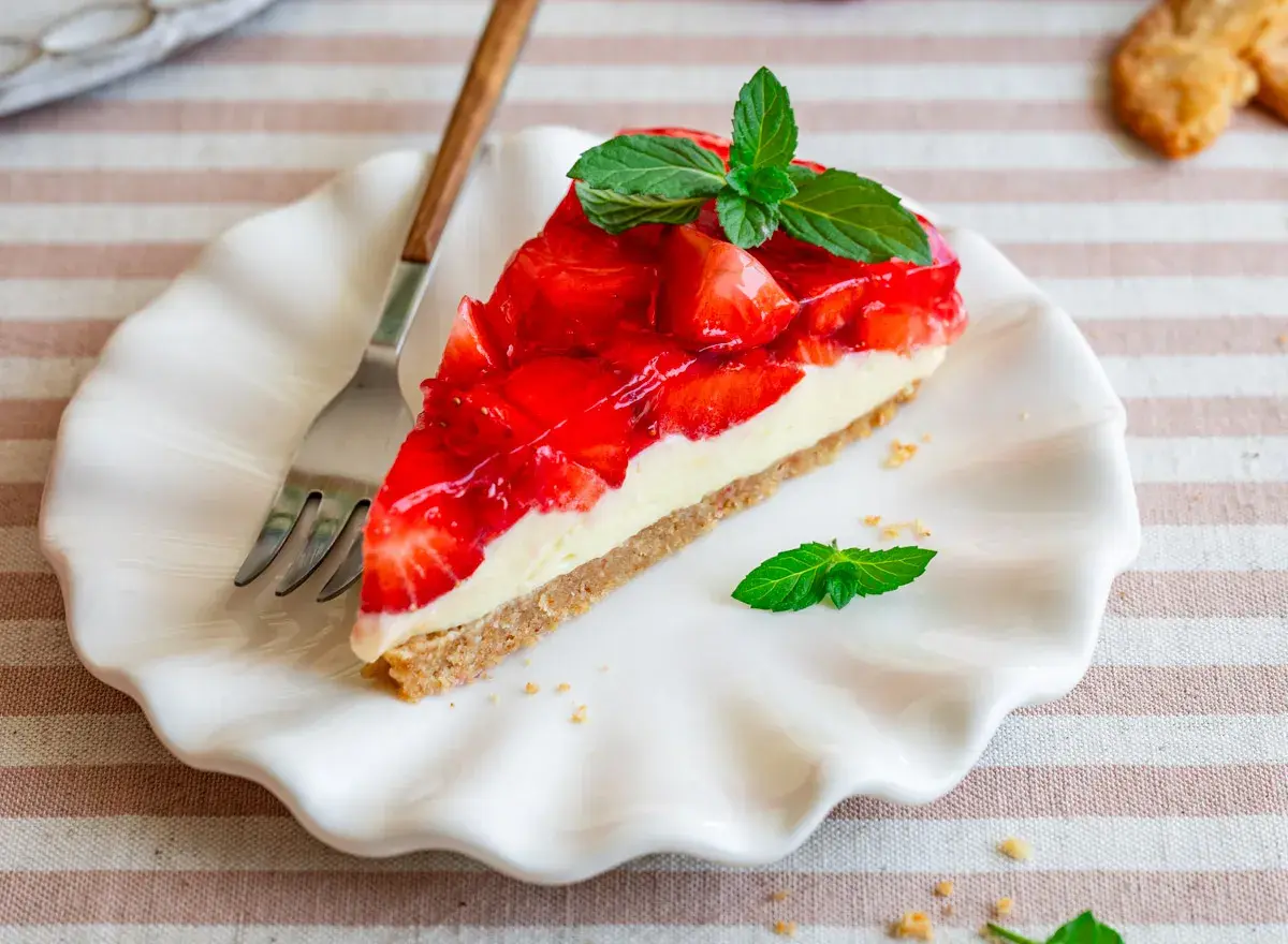 Ein Stück Erdbeerkuchen mit Keksboden, schnell und ohne Backen zubereitet. Frisch, fruchtig und mit Minze garniert.