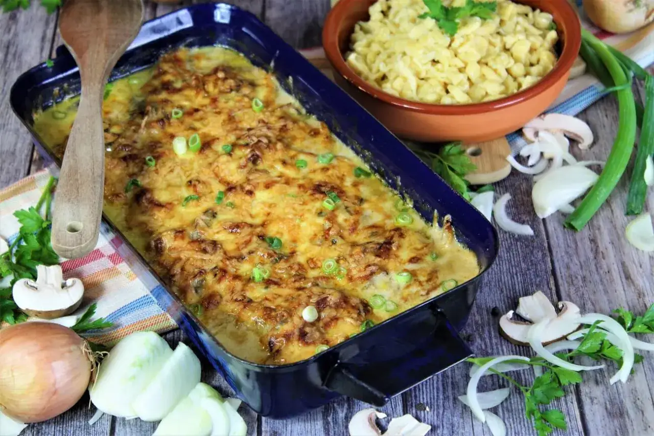 Zwiebel Sahne Schnitzel im Auflauf, goldbraun &uuml;berbacken, mit Sp&auml;tzle und frischen Zutaten daneben.