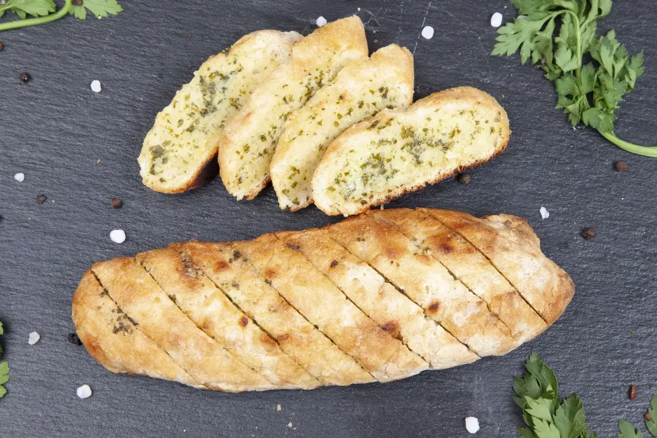 Knuspriges Baguette zum Grillen, mit Kräutern verfeinert und in Scheiben geschnitten, bereit für den Genuss.