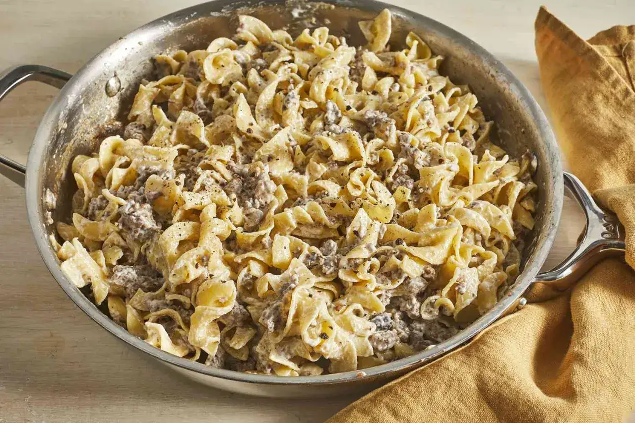 Herzhaftes, warmes schnelles Abendessen: Nudeln mit Hackfleisch in cremiger Sauce, gewürzt mit Pfeffer, in einer Pfanne.