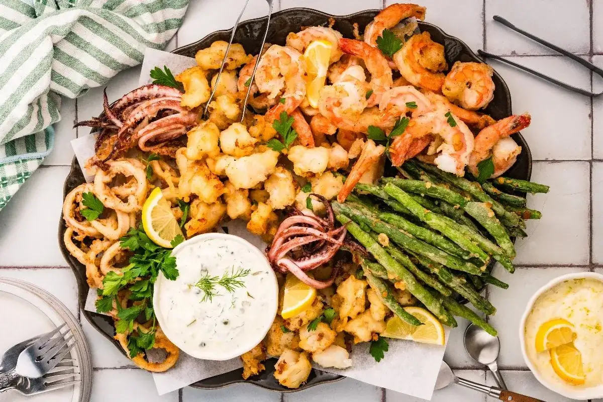 Ein k&ouml;stliches Fritto Misto mit knusprigen Garnelen, Tintenfischringen, Calamari und gr&uuml;nen Bohnen, garniert mit Zitrone und Petersilie.