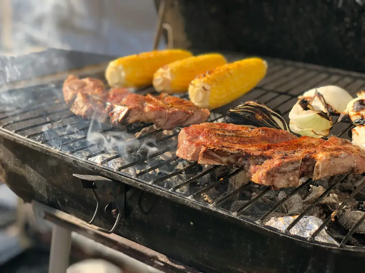 Saftige Steaks, Maiskolben und Zwiebeln brutzeln auf dem Grill. Die beste Steak Marinade sorgt f&uuml;r perfekten Geschmack.