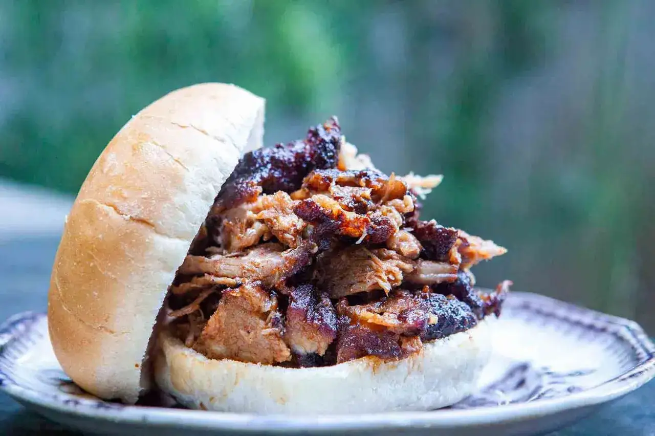Saftiges Pulled Pork, perfekt zubereitet auf dem Gasgrill, stapelt sich auf einem Brötchen. Ein Genuss für BBQ-Liebhaber.