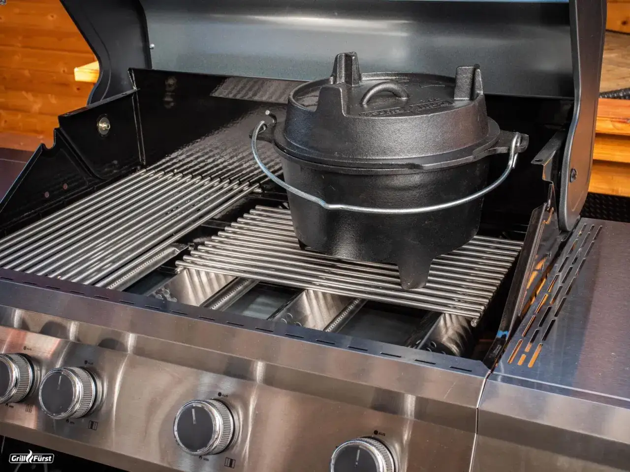 Schwarzer Dutch Oven auf dem Rost eines Gasgrills. Perfekt für deftige Eintöpfe und Brot.