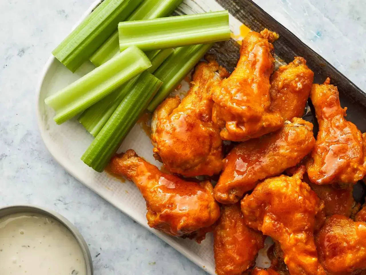 Saftige buffalo wings mit scharfer Sauce, serviert mit knackigem Sellerie und Dip.