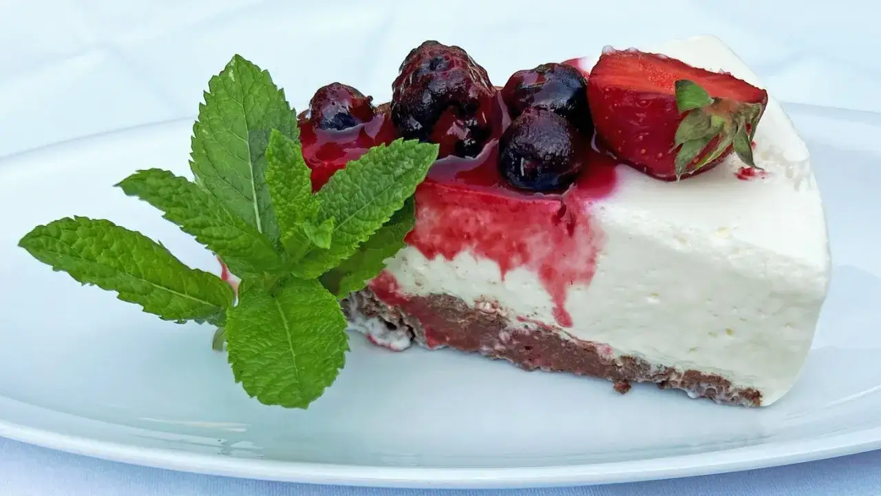 Ein St&uuml;ck cremiger K&auml;sekuchen mit Keksboden, Beeren und Minze &ndash; schnelle Kuchen ohne Backen mit Keksboden sind perfekt f&uuml;r hei&szlig;e Tage.
