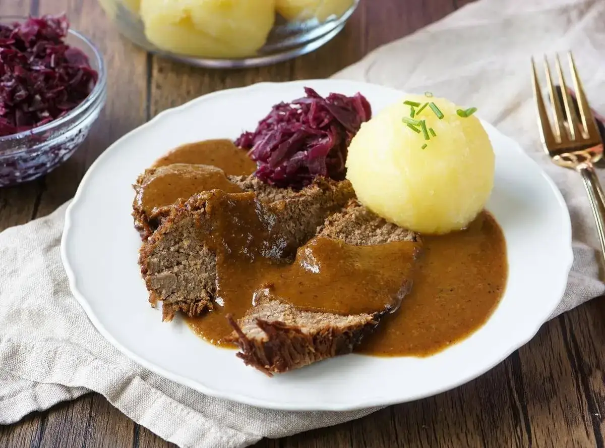 Ein Teller mit deftigem Braten, Klößen und Rotkohl – wie vergessene Rezepte aus Omas Zeiten, die auf der Zunge zergehen.