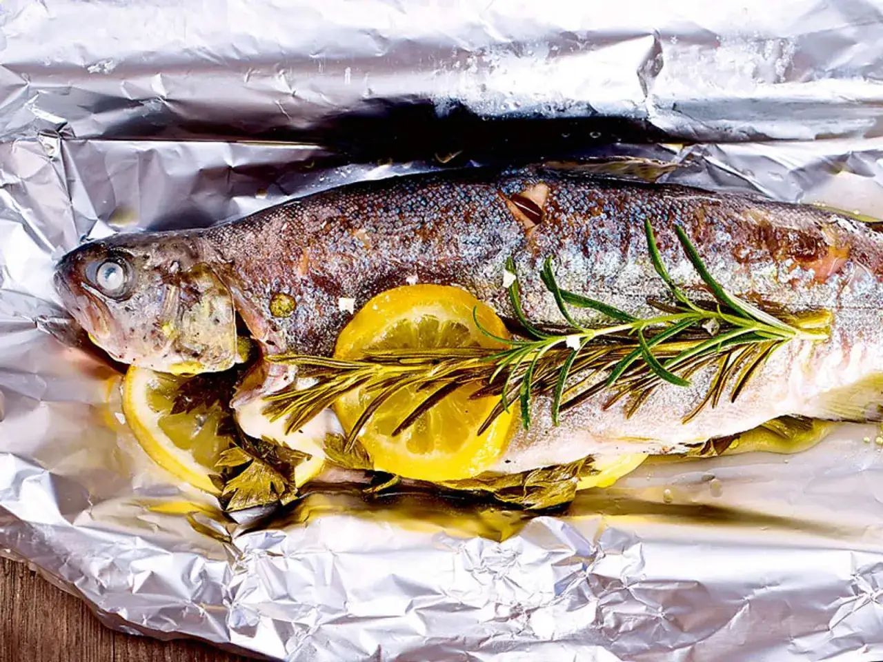 Eine ganze Forelle mit Zitrone und Rosmarin auf Alufolie f&uuml;r das Grillen vorbereitet.