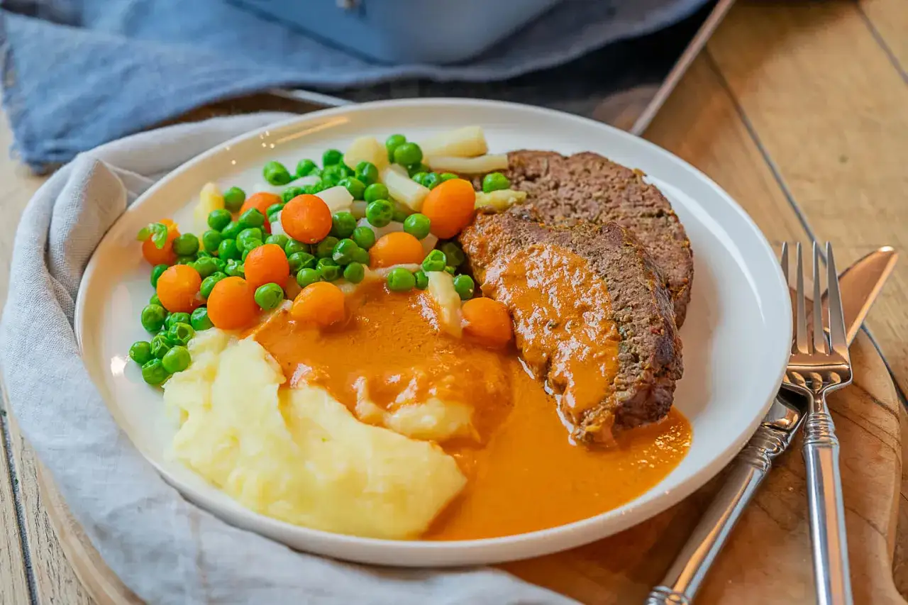 Ein saftiger Hackbraten mit Kartoffelp&uuml;ree, Erbsen und Karotten in einer cremigen Sauce. Ein klassisches Hackbraten Rezept f&uuml;r ein herzhaftes Essen.