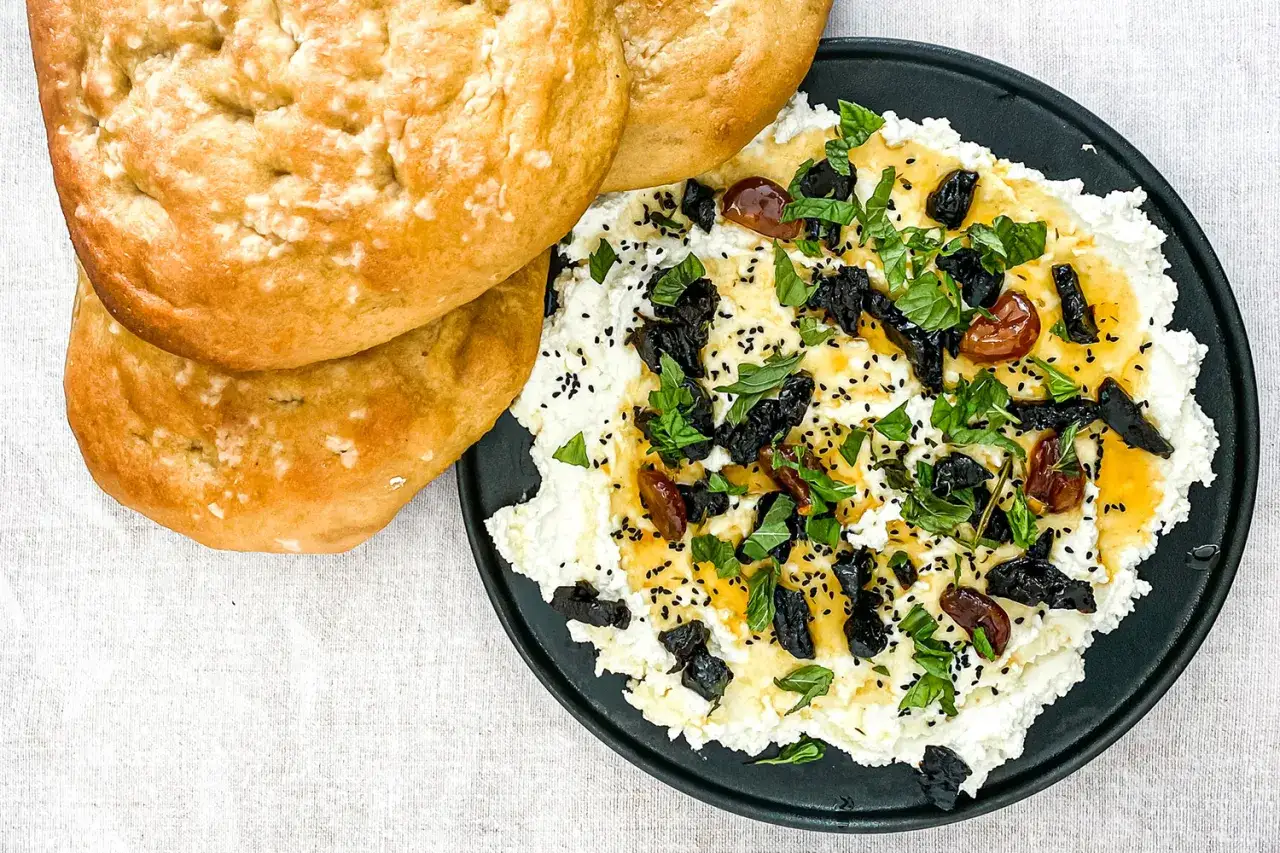 Cremiger Feta-Dip mit getrockneten Fr&uuml;chten, Kr&auml;utern und Sesam, serviert mit Fladenbrot.