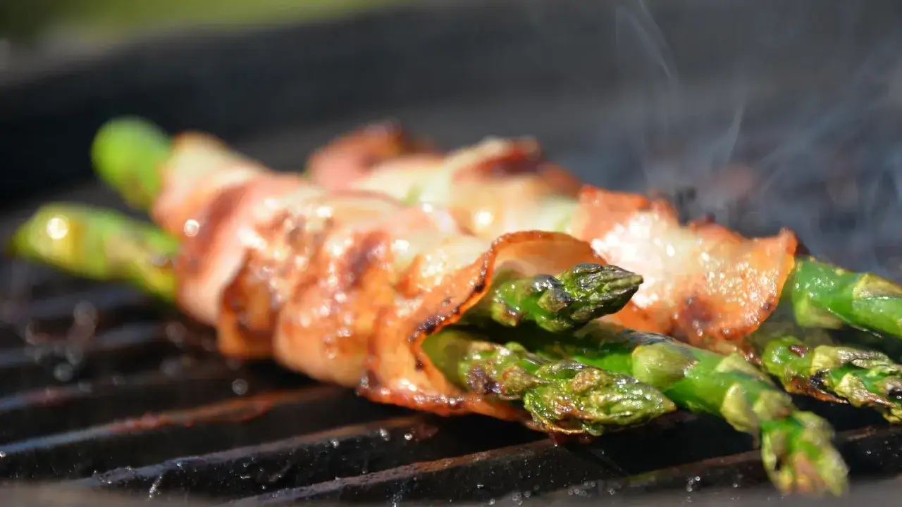 Spargel grillen auf dem Gasgrill: Gr&uuml;ne Spargelr&ouml;schen umwickelt mit Speck garen und rauchen.