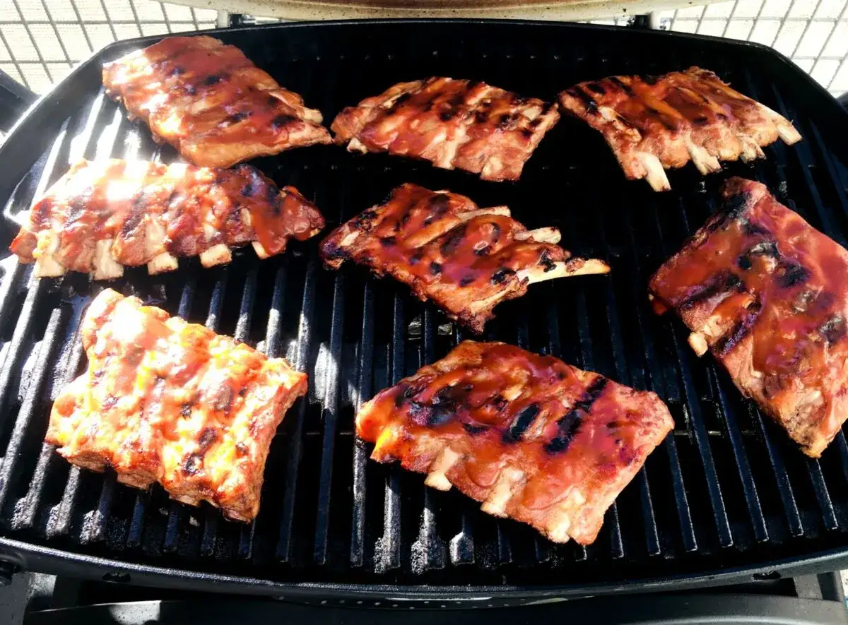 Saftige spareribs sous vide, glasiert mit BBQ-Sauce, brutzeln auf dem Grill.