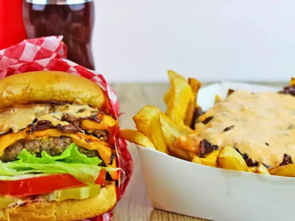 Saftiger Burger mit K&auml;se und Salat, daneben Pommes mit der ber&uuml;hmten In-N-Out Burger Sauce.