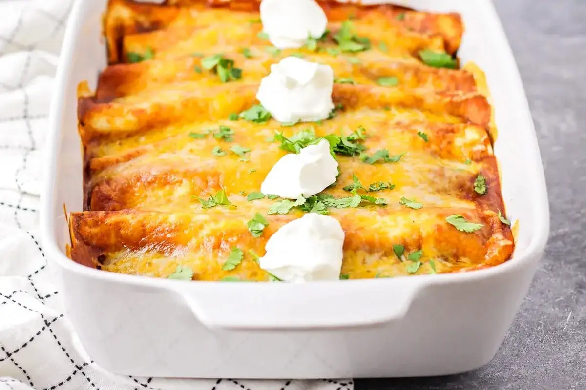 Heiß servierte Enchiladas mit geschmolzenem Käse, garniert mit Sauerrahm und Koriander. Ein köstliches Enchiladas Rezept!