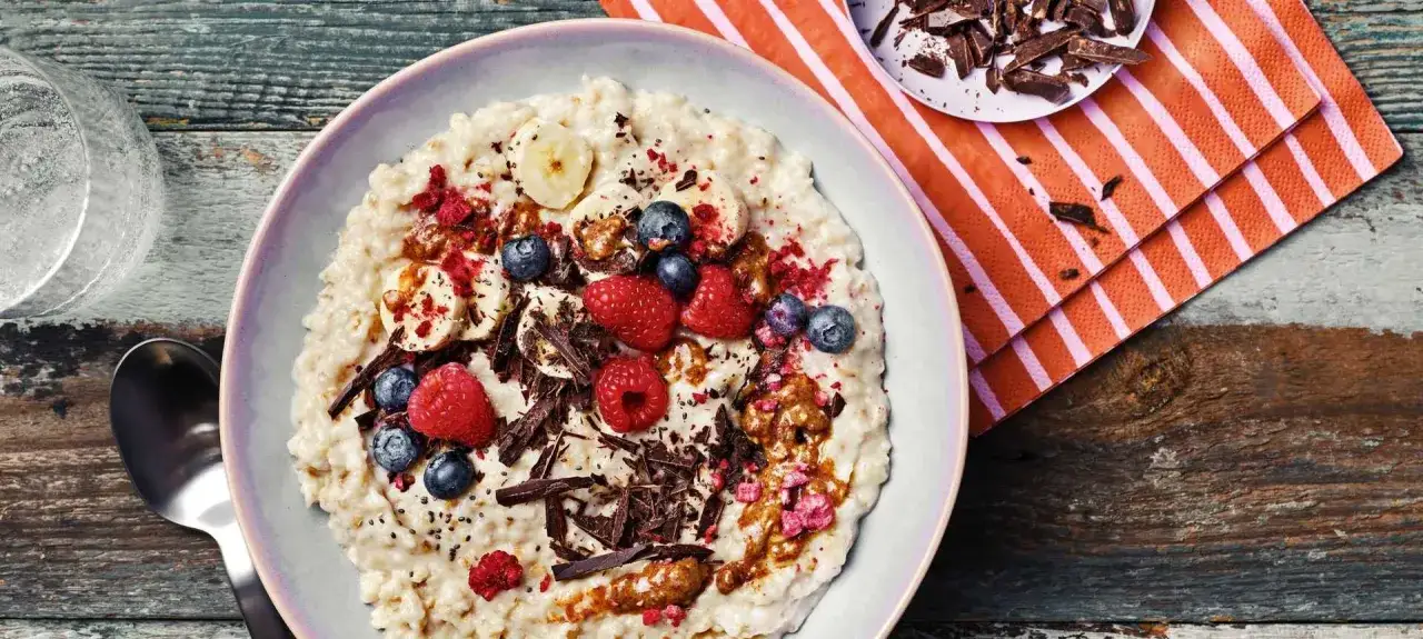 Cremiger Porridge mit Bananen, Beeren, Schokost&uuml;ckchen und Nussbutter &ndash; ein k&ouml;stliches Porridge Rezept f&uuml;r einen energiegeladenen Start in den Tag.