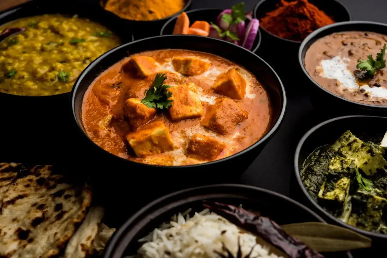 Vielfalt an indischen Gerichten: cremiges Paneer Tikka Masala, Dal Makhani, Palak Paneer, Reis und Naan.